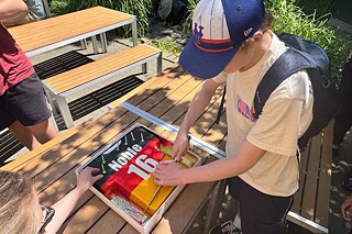 Jugendlicher mit Baseballkappe schneidet eine Torte an.