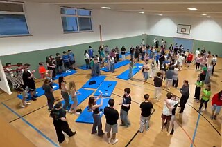 Jugendliche tanzen in einer Sporthalle.