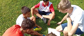 Jugendliche auf einer Wiese bei einer Projektplanung