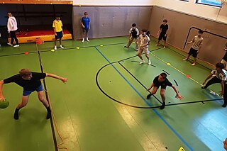 Jugendliche spielen Völkerballturnier in einer Halle.