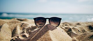 Sonnenbrille im Sand an einem Strand