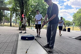 Jugendlicher spielt Minigolf.