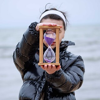 Junge Frau mit Sanduhr am Strand