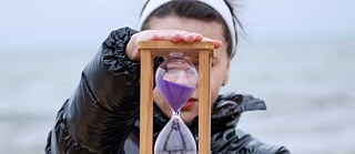 Junge Frau mit Sanduhr am Strand