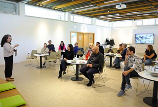 A person presenting to a seated audience in an event space.