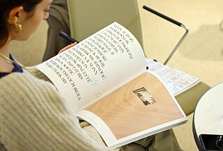 A person reading a copy of the “EVROVIZION” magazine.