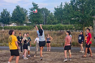Jugendliche spielen Volleyball auf einer Wiese.