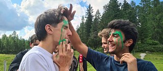 Jugendliche tragen Tarnfarbe auf.
