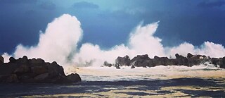 Copilot said: Une haute vague se brise contre une jetée de blocs rocheux sombres. De l’eau blanche et des embruns s’élèvent plusieurs mètres au-dessus de l’ouvrage. Au premier plan, on voit une mer sombre ; à l’arrière-plan, un ciel bleu foncé. Les couleurs dominantes de l’image sont le bleu, le blanc et le gris foncé.