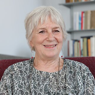 Ritratto della traduttrice Anita Raja in poltrona con libreria sullo sfondo