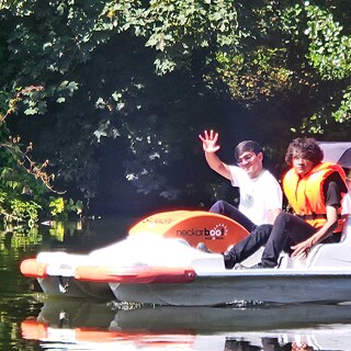 Jugendliche fahren Tretboot auf dem Neckar.