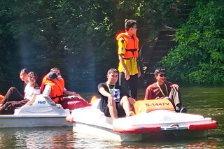 Jugendliche fahren Tretboot auf dem Neckar.