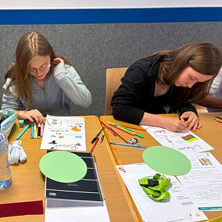 Zwei Jugendliche arbeiten konzentriert an einem Tisch in einem Unterrichtsraum.