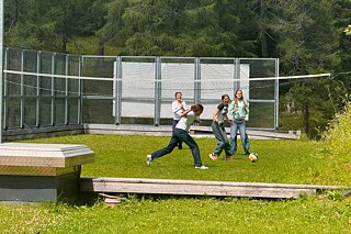 Jugendliche spielen Ball auf einer Wiese.