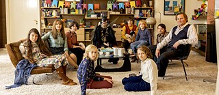 Gruppenfoto von Erwachsenen Kindern, manche kostümiert in einem Wohnzimmer
