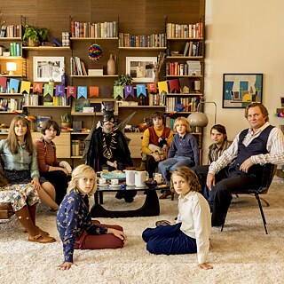Gruppenfoto von Erwachsenen Kindern, manche kostümiert in einem Wohnzimmer