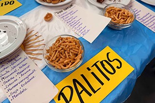 Salziger Snack aus Argentinien; daneben stehen leere Teller mit weiteren Spezialitäten aus dem Land.