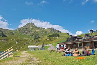 Jugendliche machen eine Pause auf einer Wiese in den Alpen.