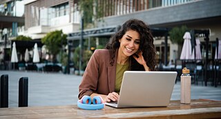 Eine Frau arbeitet am Laptop. Sie lächelt zufrieden
