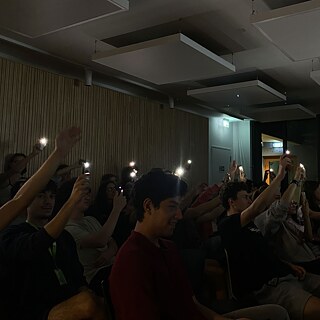 Jugendliche halten ihre Smartphones mit Taschenlampe in die Höhe.