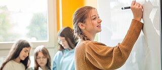 Vier Schülerinnen arbeiten gemeinsam an einem Smartboard