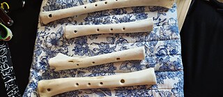 Vier historische Knochenflöten liegen auf einem blau-weiß gemusterten Stofftuch auf einem Tisch.