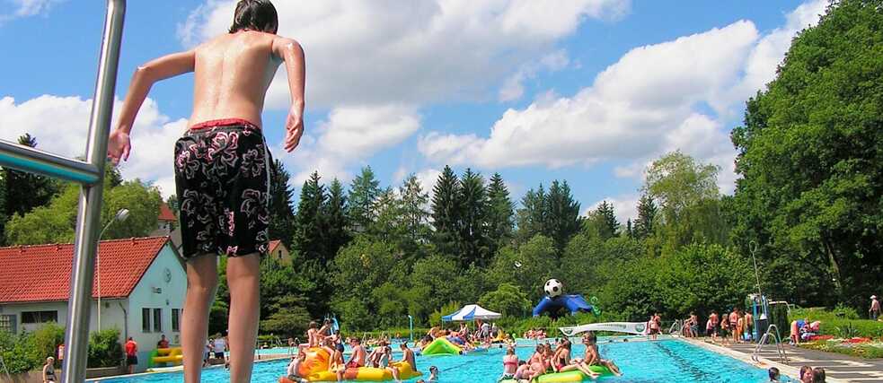 Summer, sunshine, outdoor pool: teenagers enjoy a jump into the cool water, a classic part of a German summer. 