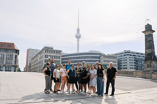 The TOP 1 2026 group poses on a bridge in Berlin with the TV tower in the background.