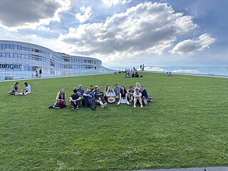 The TOP 2 2026 study tour group sits on an urban grass field.