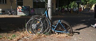 A non-functional bike leaning against a steel pole in the city-scape