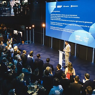 A large audience gathered around a speaker at the Film und Medien Stiftung NRW stand during Games Connect Africa.