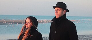 Žena i muškarac stoje na plaži u zimu.