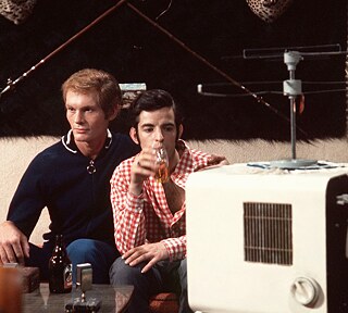Two people sit closely together on a sofa and watch tv.