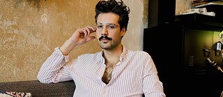 Forfatteren Ozan Zakariya Keskinkılıç sidder i en sofa.