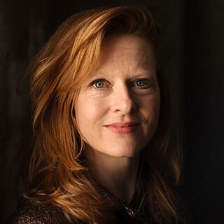 Porträtfoto der Autorin Anja Kampmann, die im Rahmen der Reihe „Meet the Author“ ihr Buch Die Wut ist ein heller Stern vorstellt. Die Aufnahme zeigt die Autorin in einer Nahaufnahme vor dunklem Hintergrund. Das Gesicht und die hellen Haare werden von warmem Licht hervorgehoben. Die Autorin blickt direkt in die Kamera.