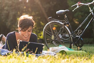 Junge Frau auf einer Wiese mit dem Laptop