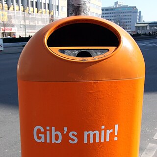 Ein orangener öffentlicher Mülleimer mit der Aufschrift "Gibs mir".
