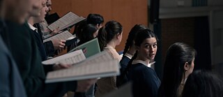 Ein Mädchen schaut aus dem Chor heraus Richtung Kamera.