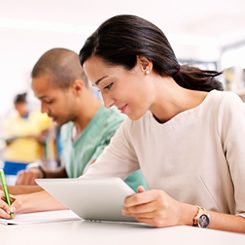 Eine junge Frau in einem Klassenzimmer macht sich Notizen.