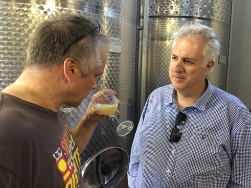 Winzer und Reporter vor den Weintanks