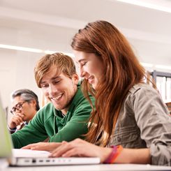 Två unga språkstudenter sitter vid en dator.