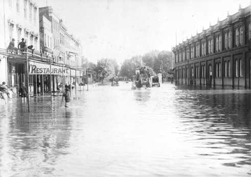 Flut, 200 Block der 7th Street NW, 1889, südlicher Blick von der Mall. Die Flut kann die Pferdewägen nicht aufhalten. Jungen und Männer scheinen Spaß dabei zu haben, den Pferden dabei zuzuschauen, wie sie sich ihren Weg durch das Wasser bahnen. Der Center Market ist auf der rechten Seite erkennbar.