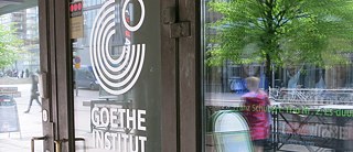 Katu heijastuu Goethe-Institut Finnlandin lasiseen ulko-oveen.