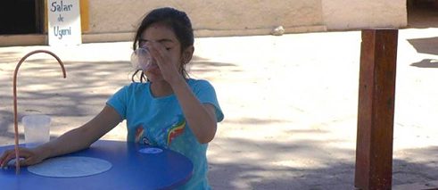Ein Mädchen trinkt Wasser aus dem FreshWater Gerät in San Pedro de Atacama, Chile.