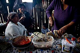 Die Pehuenche. Im Inneren der Ruca: Juana schneidet das in Asche gebackene Brot auf, um mit dem Frühstück zu beginnen. Es besteht aus Tunfisch mit Zwiebeln, fritierten Tomaten und gesalzenem Ají (eine Art von Chili). 