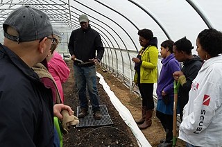 Ředitel farmy Firebird, Mchezaji „Che“ Axum, studenty učí, jak uhrabávat záhony. 