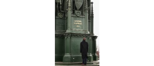 Tarnished inscription, glistening in golden letters behind him...