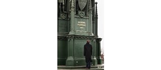 Tarnished inscription, glistening in golden letters behind him...