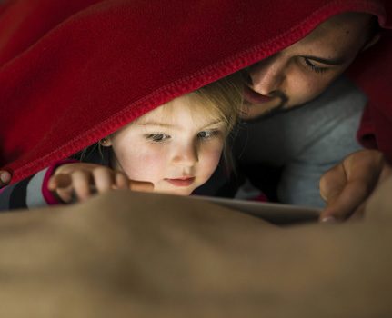 Vater und Tochter mit Tablet unter der Decke