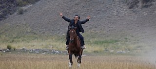 Le personnage principal du film, les bras écartés sur son cheval dans le Kirghizistan 